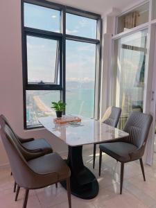 une table et des chaises dans une chambre avec une grande fenêtre dans l'établissement Gold Beach Nha Trang Apartment, à Nha Trang