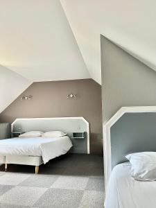 a bedroom with two beds and a sloped ceiling at Hôtel La Tour des Anglais in Mayenne