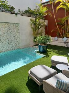 a backyard with a swimming pool with grass and chairs at Villa Zawaia B&B in Lagos