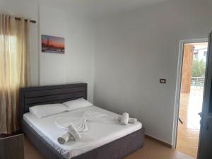 Vila Bashkim في كساميل: غرفة نوم بسرير ذو شراشف ووسائد بيضاء