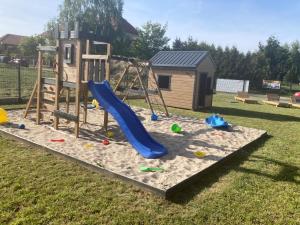 a playground with a slide in the sand at Domki Kalimera Rewal in Rewal