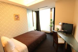 東京にあるホテルリブマックスBUDGET後楽園のベッド、デスク、テレビが備わるホテルルームです。