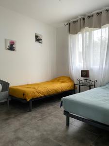 a bedroom with two beds and a window at Villa MIMOSA in Sampzon