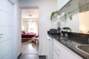 eine Küche mit weißen Schränken und einer schwarzen Arbeitsplatte in der Unterkunft King David Apartment - J&J in Jerusalem