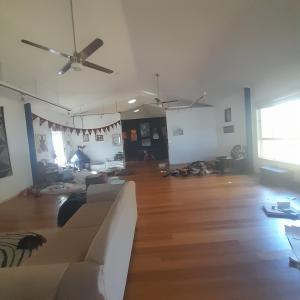 a living room with a couch and a ceiling fan at Bitolovo The Blue House in Nimbin