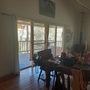 a living room with a table and some windows at Bitolovo The Blue House in Nimbin