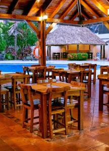 a restaurant with wooden tables and chairs and a pool at Hotel Maria Gloria in Villavicencio