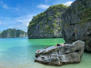 a person laying on a rock in the water at Tran Chau Garden Home in Cat Ba
