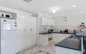 a kitchen with white cabinets and a white refrigerator at Southern Comfort Lodge Victor Harbor in Victor Harbor