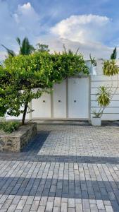 un bâtiment avec des portes de garage blanches et un arbre dans l'établissement Shades Hotel & Villa, à Matara