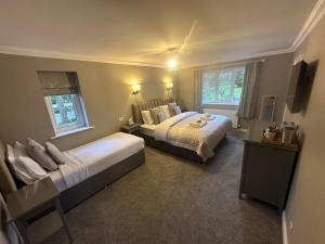 een slaapkamer met 2 bedden en 2 ramen bij Burton Lodge Guest House & Spa in Brandesburton