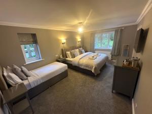 a bedroom with two beds and two windows at Burton Lodge Guest House & Spa in Brandesburton