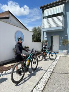 dos personas de pie con sus bicicletas fuera de un edificio en B&B Il Granaio Celeste, en Porto Viro