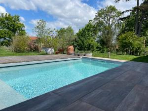 a swimming pool in the backyard of a house at La Grange aux hirondelles - appartement complet et indépendant in Commelle-Vernay