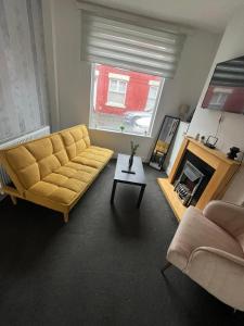 uma sala de estar com um sofá amarelo e uma lareira em Perfect for Contractors' Accommodation em Seacombe