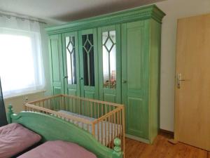 a bedroom with a green cabinet with a bed in it at Ferienwohnung II, Schloßstraße Kottmarsdorf in Kottmarsdorf
