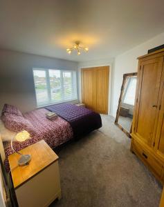 1 dormitorio con cama morada y armario de madera en Whiteclouds, en Cheshunt