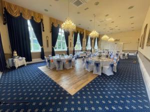 a banquet hall with tables and chairs and chandeliers at Bestwood Lodge Hotel in Nottingham