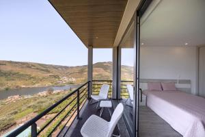 1 dormitorio con 1 cama y sillas en el balcón en Feel Discovery Alvim's Douro en Folgosa