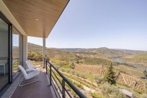 a balcony with two chairs and a view of a river at Feel Discovery Alvim's Douro in Folgosa