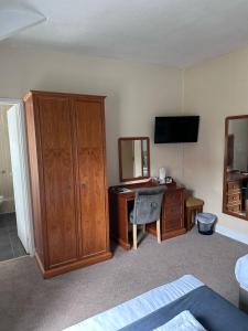 1 dormitorio con escritorio, armario y TV en East Ayton Lodge Hotel, Scarborough, en Scarborough