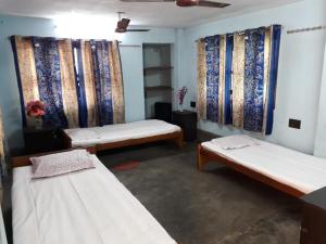 um quarto com três camas com cortinas em Pushpak Guest House Boys, Near DumDum metro Station em kolkata