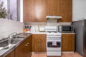 una cucina con armadi in legno e un piano cottura bianco con forno di Quiet 2BR Apartment with Garden views in Griffith - Hosted by CanStay a Kingston 