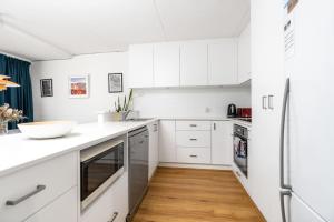 a white kitchen with white cabinets and a wooden floor at Stylish apt facing the historic Telopea Park - Hosted by CanStay in Kingston 