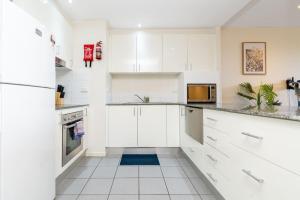 Una cocina blanca con gabinetes y electrodomésticos blancos. en Charming Apt 1min to Marketplace Gungahlin - Hosted by CanStay, en Harrison