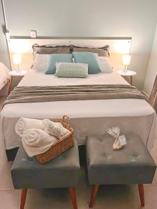 1 cama grande con 2 reposapiés y toallas en Pousada da Bia Praia, en Penha