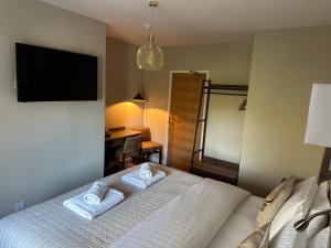 een slaapkamer met een wit bed en handdoeken bij Burton Lodge Guest House & Spa in Brandesburton