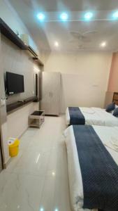 um quarto de hotel com duas camas e uma televisão de ecrã plano em Goroomgo Prakash Residency Varanasi Near Kashi Vishwanath Temple em Varanasi