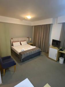 una camera con letto, sedia e televisore di Flat Alphaville - ComfortSuites a Barueri