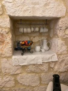 un mur avec une étagère avec des tasses et une corbeille de fruits dans l'établissement Il Trullo di Loa ad Ostuni a soli 10km dal mare, à Ostuni