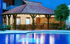 einen Pool mit einem Pavillon mit einem Tisch und Stühlen in der Unterkunft Hotel Maria Gloria in Villavicencio