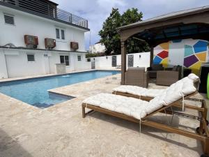 a pool with two chaise lounges and an umbrella at Sea Breeze Tunnel Hideaway 7 in Quebradillas