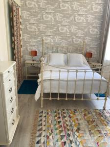 Gulls Wing Apartment في فنتنور: غرفة نوم بسرير وطاولتين وجدار