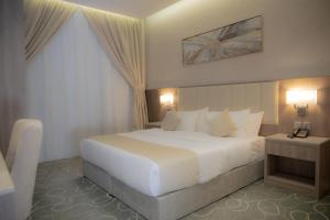 ein Schlafzimmer mit einem großen weißen Bett und zwei Lampen in der Unterkunft فندق نارس بلس النزهة - Nars Plus Hotel in Dschidda