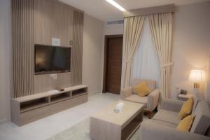 a living room with a tv and a couch and a table at فندق نارس بلس النزهة - Nars Plus Hotel in Jeddah