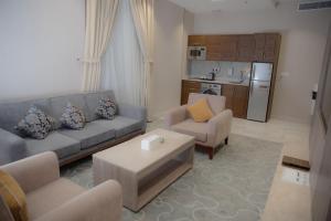 فندق نارس بلس النزهة - Nars Plus Hotel في جدة: غرفة معيشة مع أريكة وكراسي وطاولة