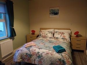 a bedroom with a bed with a floral bedspread at Pegs Cottage in Limerick