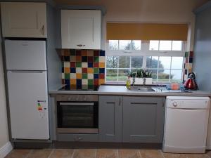 a kitchen with white appliances and a sink at Pegs Cottage in Limerick