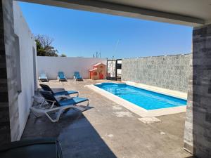 a swimming pool with two lounge chairs next to a wall at Chaletpiscina in Benicarló