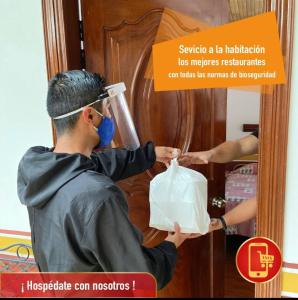 Een man stopt een zak in een deur. bij Hotel Metropolitano in Loja