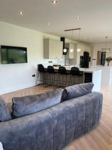 a living room with a couch and a kitchen at The Rutland House South Luffenham in Oakham