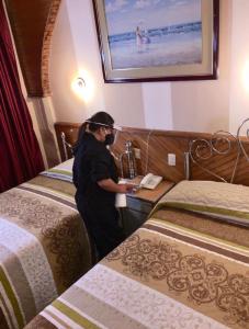 een persoon aan een bureau in een kamer met twee bedden bij Hotel Metropolitano in Loja