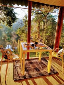 Casa de Vidro com cachoeira في إتياتيبا: طاولة وكراسي في غرفة مع نافذة كبيرة