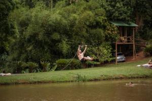 Ein Mann hängt an einem Seil über einem Fluss in der Unterkunft Casa de Vidro com cachoeira in Itatiba