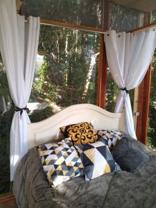 1 cama con 2 almohadas y ventana en Casa de Vidro com cachoeira, en Itatiba