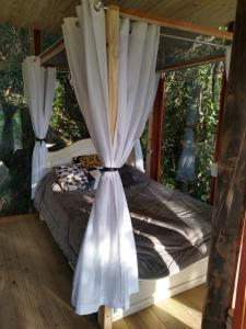 1 dormitorio con cama con dosel y cortinas en Casa de Vidro com cachoeira en Itatiba